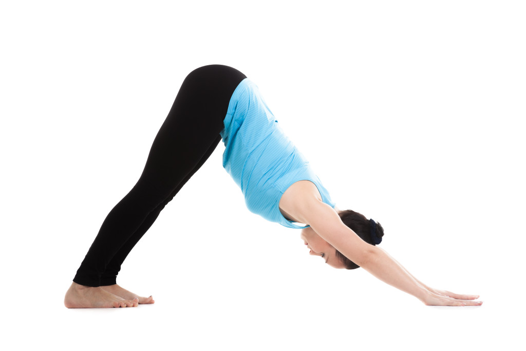 Sporty yogi girl doing yoga exercises stretching in pose adho mukha shvanasana (downward-facing dog, downward dog, down dog), isolated on white background