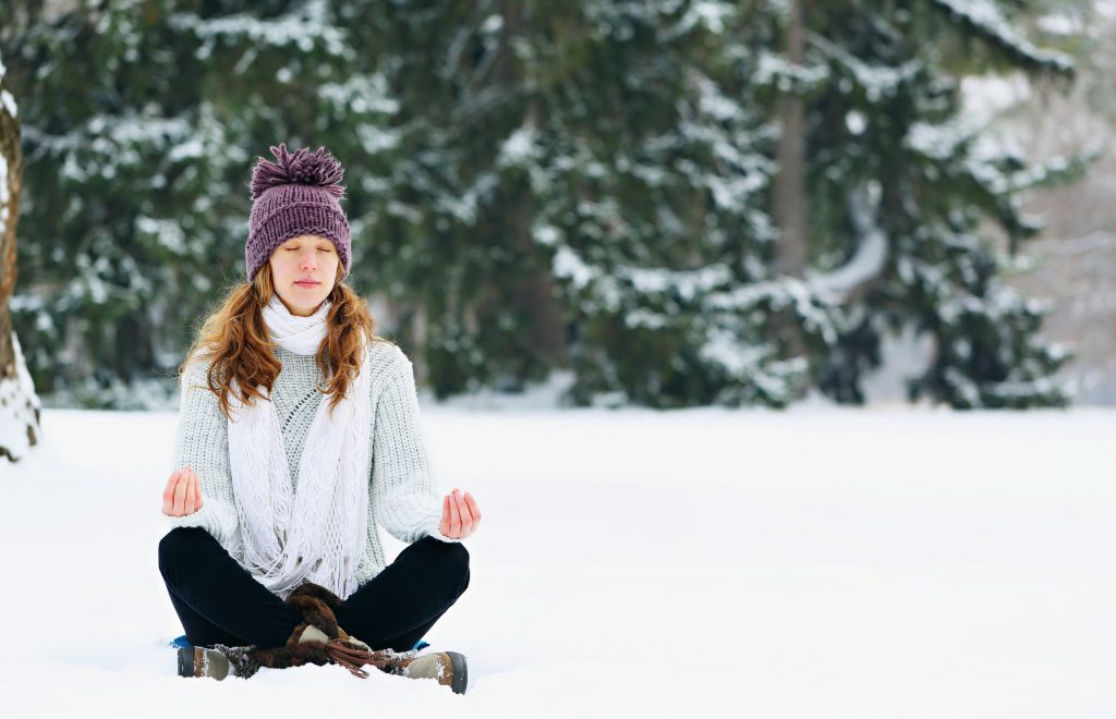 Young woman sitting and meditating at the park in winter