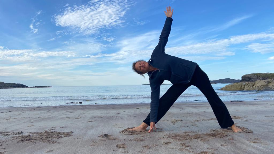Positive Female Practising Yoga Poses At Seaside In Evening